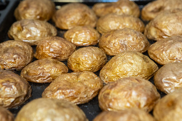 Baked spicy potatoes on baking tray, close-up, selective focus