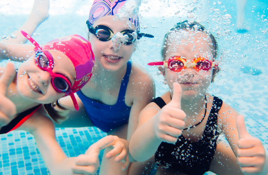 Underwater photo of young friends in swimming pool.