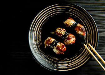 delicious sushi with eel on a black plate and a black wooden background