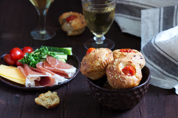 Fototapeta na wymiar Muffins with cheese, cottage cheese and tomatoes, vegetables and cheese served with wine.