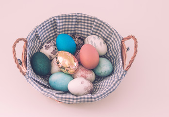 Wicker basket with colored Easter eggs on a light background
