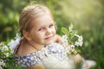 Fototapeta premium baby girl walks in spring in a blooming garden, happy childhood, cherry blossoms, month of may
