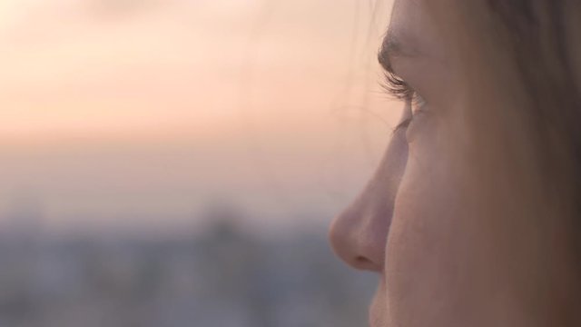 A woman looks out at urban city in the distance as day turns to night Golden Hour With Clouds 180fps