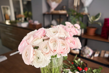 Persian buttercup. Bunch pale pink ranunculus flowers. Vase on vintage wooden table. Floral shop concept . Flowers delivery.