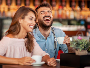 Fototapeta premium Young couple sitting at cafe table and having coffee together.