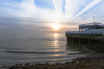 Germany, Cuxhaven - wooden pier in harbor, illuminated by morning sun, sea with waves, beautiful...