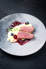 Traditionelles Gourmet Entenbrust Filet mit Kartoffel Püree und Preiselbeeren Sauce als closeup auf einem Modern Design Teller