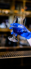 Hand in gloves holding glass in bar or cafe