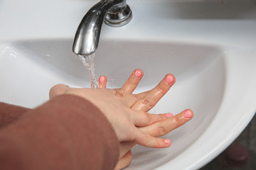 Female hands in a washstand under a stream of water