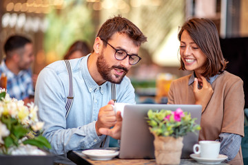 Couple have fun while looking on laptop at cafe