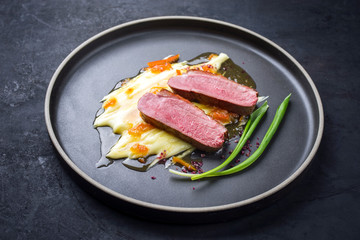 Traditionelles Gourmet Entenbrust Filet mit Kartoffel Püree und Orangen Sauce als Draufsicht auf einem Modern Design Teller mit Textfreiraum 