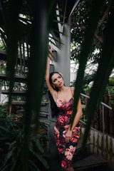 A young beautiful brunette poses near a spiral staircase in the Botanical garden among the dense thickets of the tropic forest. Spa