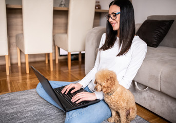 Young woman working at home with her pet.
