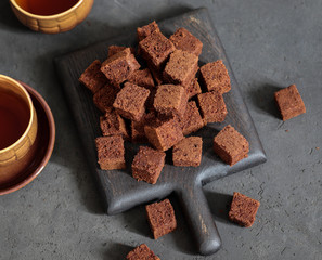 Dessert chocolate biscuit cut into cubes with coffee on a dark gray background top view