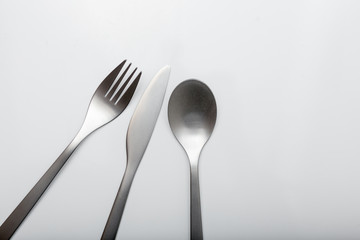 Cutlery on white table. Minimal designed fork, knife and spoon on clear, white background