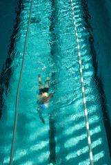 Nadador nadando a crol en una piscina cubierta.