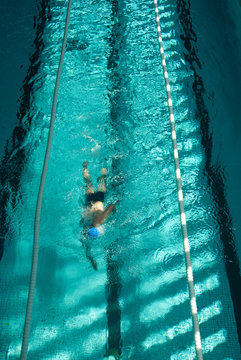 Nadador nadando a crol en una piscina cubierta.