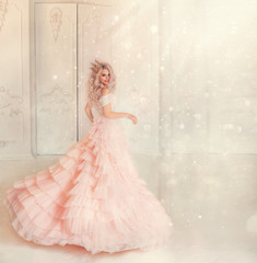 Happy young woman princess dancing in lush vintage pink dress. white royal room. Queen blond hair, golden crown. Light magic sparkles shiny. Carnival holiday invitation gesture. Background free space © kharchenkoirina