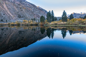 Obraz premium reflecctive mountain lake with pines aspens grass and mountain