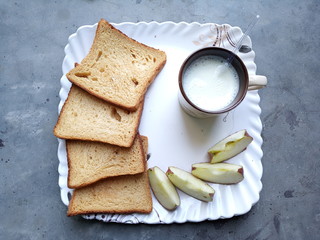 fresh home breakfast breads and apples with milk in cup on white plate