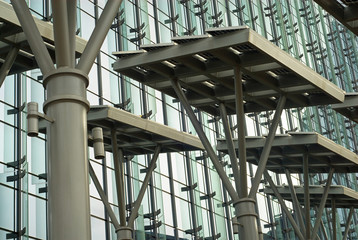 Fototapeta premium Tall stands in front of a building holding solar panels.