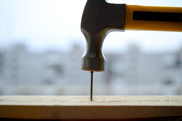 A powerful hammer hammers a nail into a wooden board.