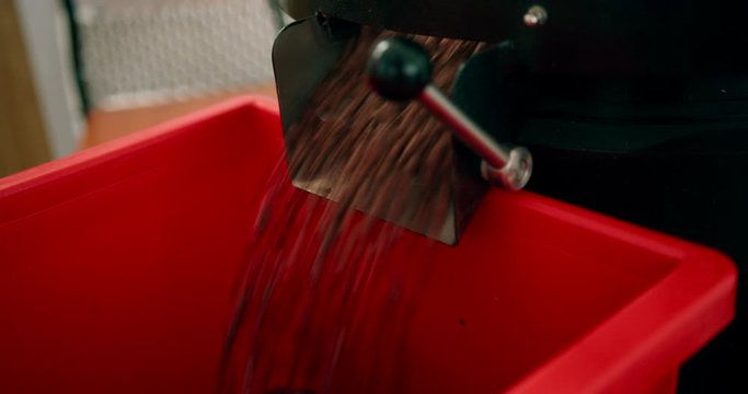 Spilling freshly roasted coffee from the tank. Close up.