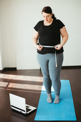 Weight loss, overweight, plus size, diet. Fat woman measures her waist with measuring tape after...