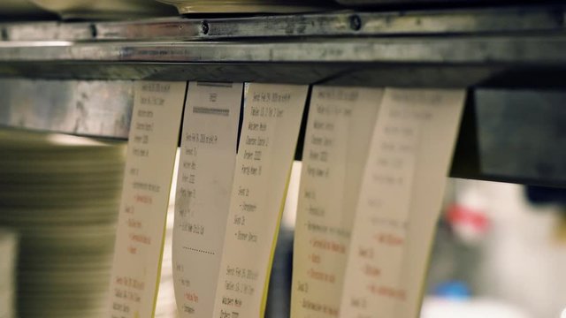 Hanging ticket tabs on restaurant kitchen. Close up hand held video of ticket tabs.
