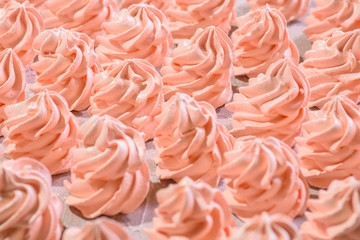 Delicious pink freshly made meringues lined up symmetrically on a concrete background. Pattern.