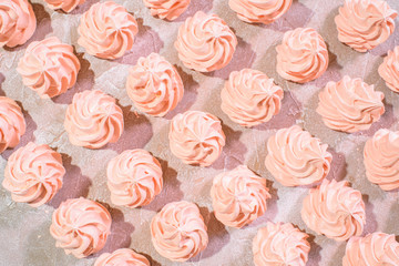 Delicious pink freshly made meringues lined up symmetrically on a concrete background. Pattern.