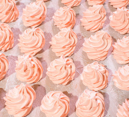 Delicious pink freshly made meringues lined up symmetrically on a concrete background. Pattern.