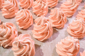 Delicious pink freshly made meringues lined up symmetrically on a concrete background. Pattern.