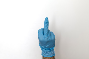 Mittelfinger und Hand in Gummihandschuh zum Schutz gegen Corona Virus