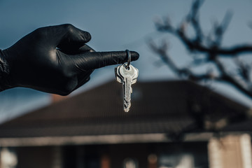 Keys in hand in black glove. Use alcohol spray to corona virus and kill germs at the key of the...