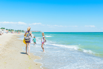 Obraz na płótnie Canvas Mom with children - a boy and a girl on the beach, the ocean.