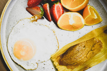 Mexican breakfast made with tamal, egg and fresh fruit.