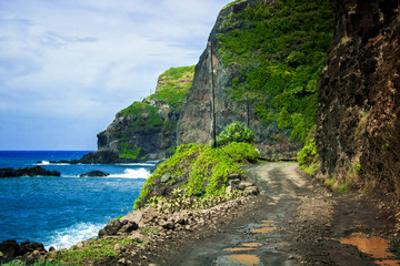 Dirt and Gravel Road Between Ocean and Cliffs in Hawaii - 336534740