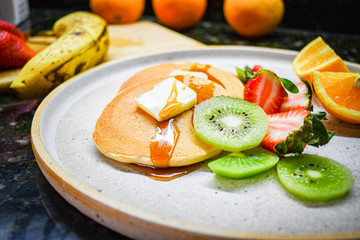 Hot cakes with strawberries, kiwi, orange and honey 