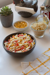 Pasta salad with yogurt and tomato sauce, corn and green onion on white background