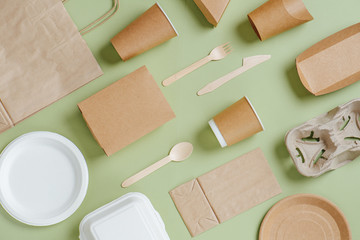 Eco-friendly disposable dishware and bamboo utensils over green background