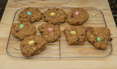 Homemade oatmeal chocolate chip cookies with an Easter mini egg sitting on top of a wooden cutting board