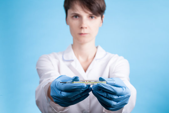 Doctor's hand in a bkue gloves holding thermometer indicating a high temperature