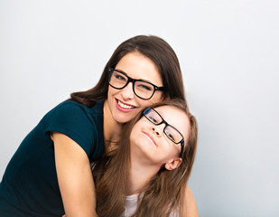 Young casual toothy smiling mother and happy kid in glasses hugging on light blue background. Closeup studio portrait. Teaching kids staying at home. Online education.