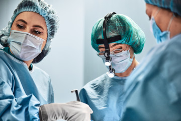 A surgeon s team in uniform performs an operation on a patient in the clinic of the center.
