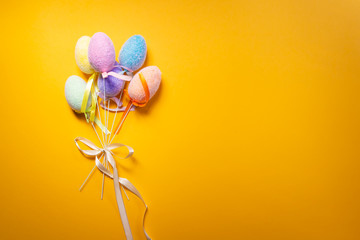 Bouquet of fluffy colorful plastic eggs isolated on yellow background.
