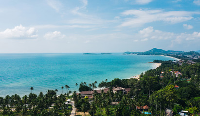 Aerial scenery view of white sand shore with turquoise clear sea water. Bird's eye panoramic view of picturesque lagoon with hotels on beach. Populated island in Thailand