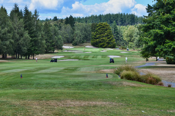 Golf  Course Hole with Golf Carts at a Safe Distance from Golfers on the Green