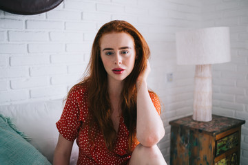 Confident woman in red dress sitting in bright room