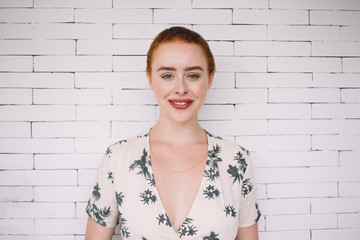 Portrait of cheerful female near brick wall